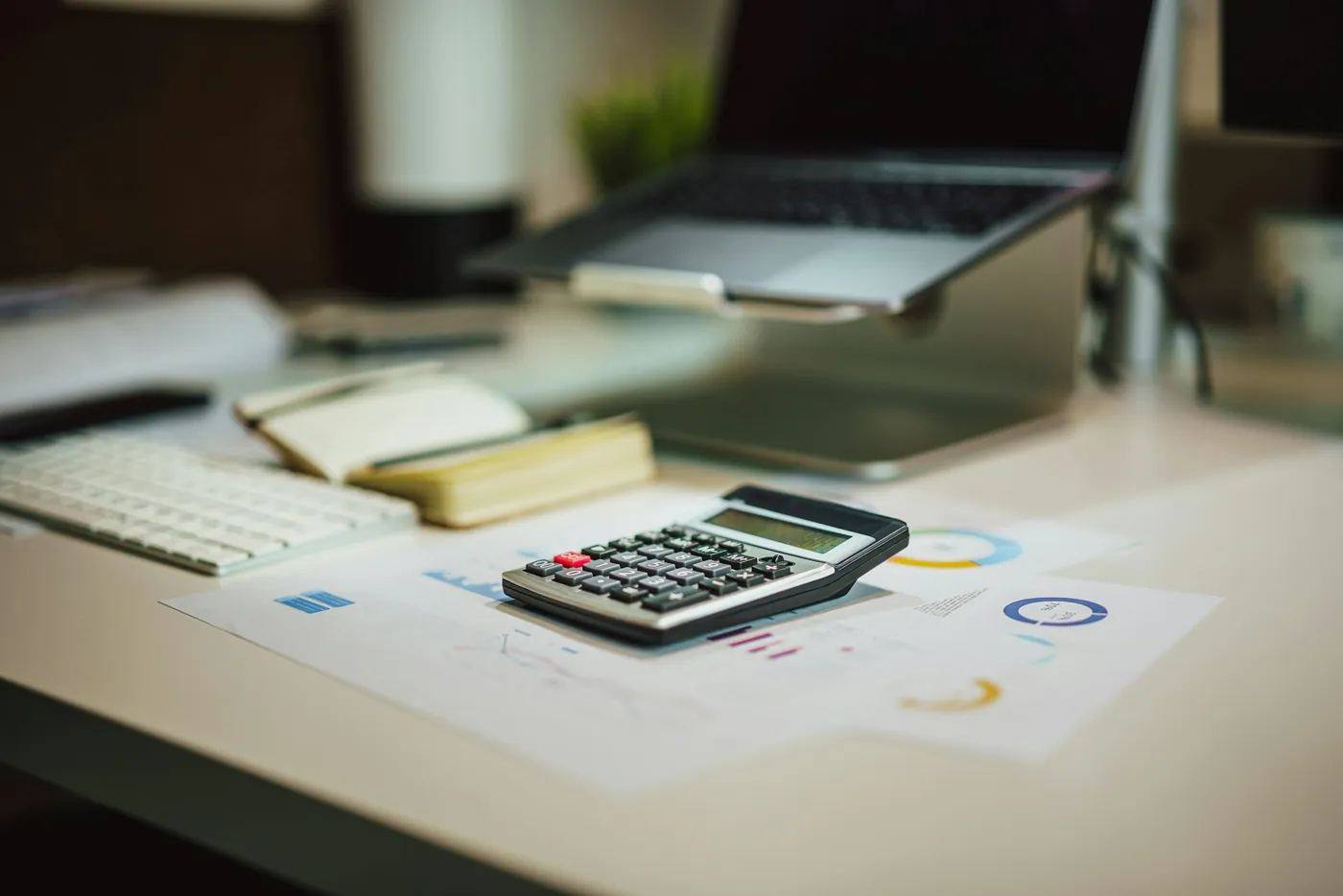 Calculator, notebook and laptop on a clean desk